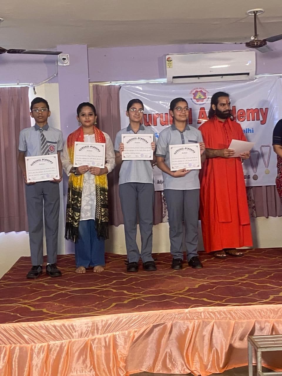 Students lined up on stage holding academy certificates