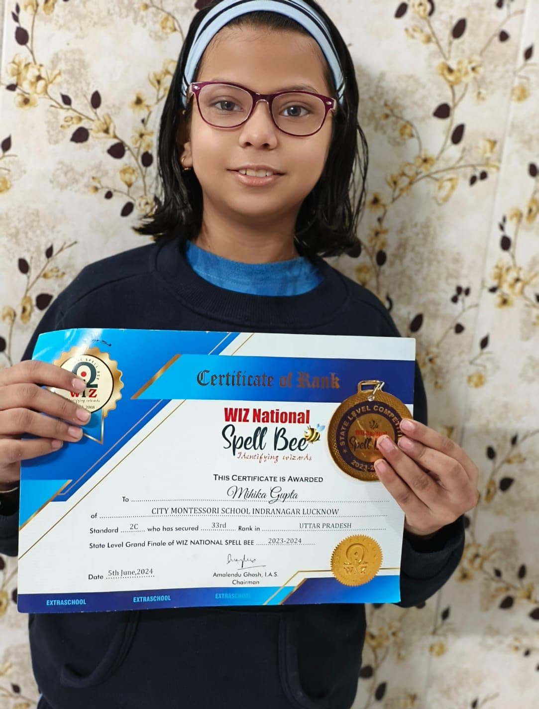 Student holding a WIZ National Spell Bee state-level rank certificate and medal