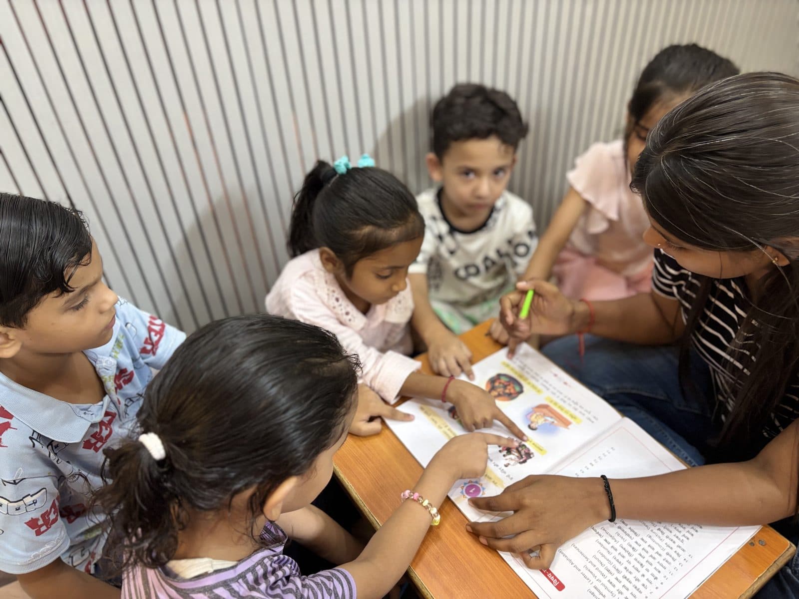 A Fusion Academy teacher guiding young students through an activity book