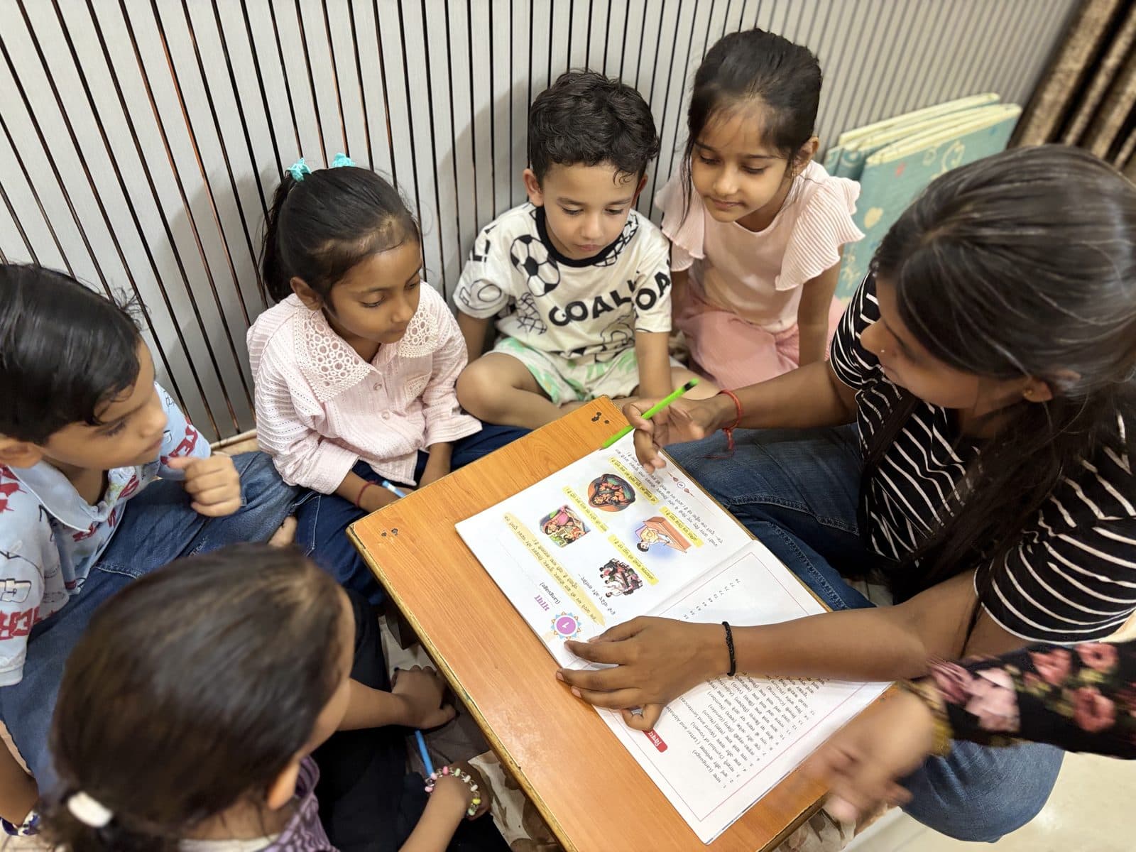 Young students gathered around a low table with their teacher